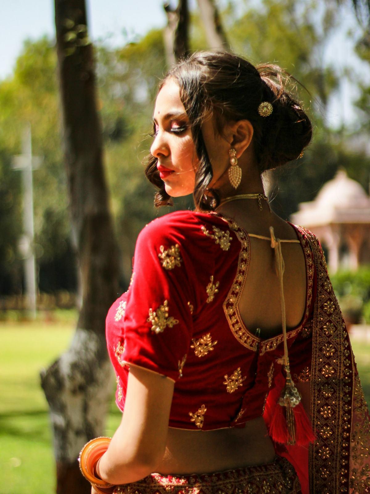 Bride in a red blouse looking over her shoulder in a palace garden