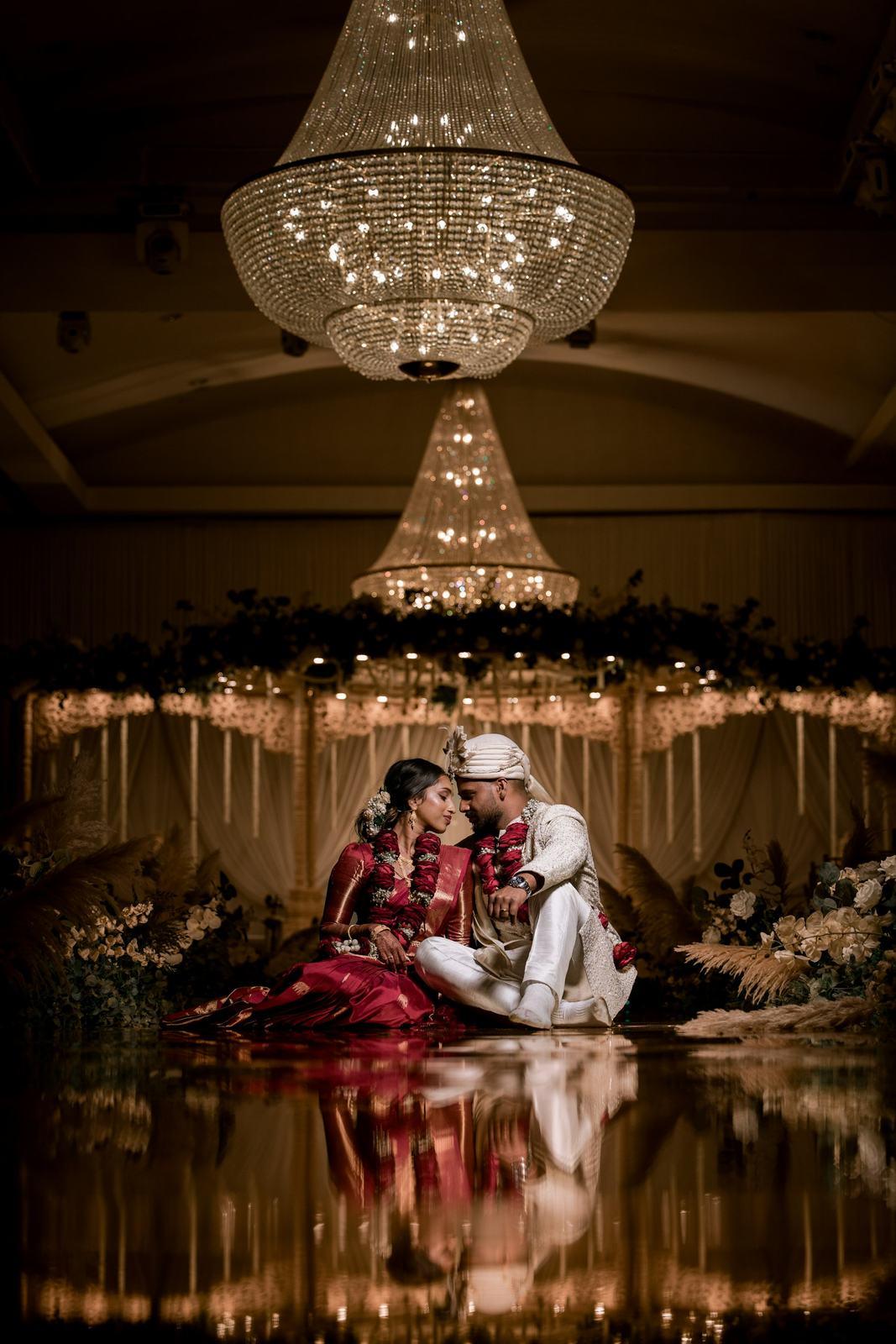 Couple sitting under chandeliers in a candle-lit hall