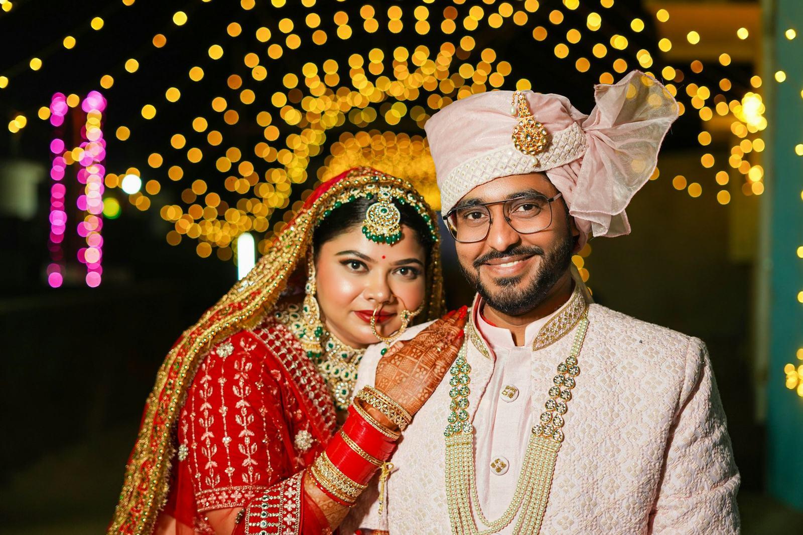 Bride and groom smiling under a canopy of fairy lights