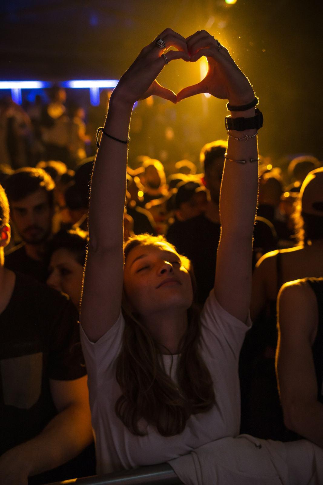 Concert crowd with a fan making a heart with her hands