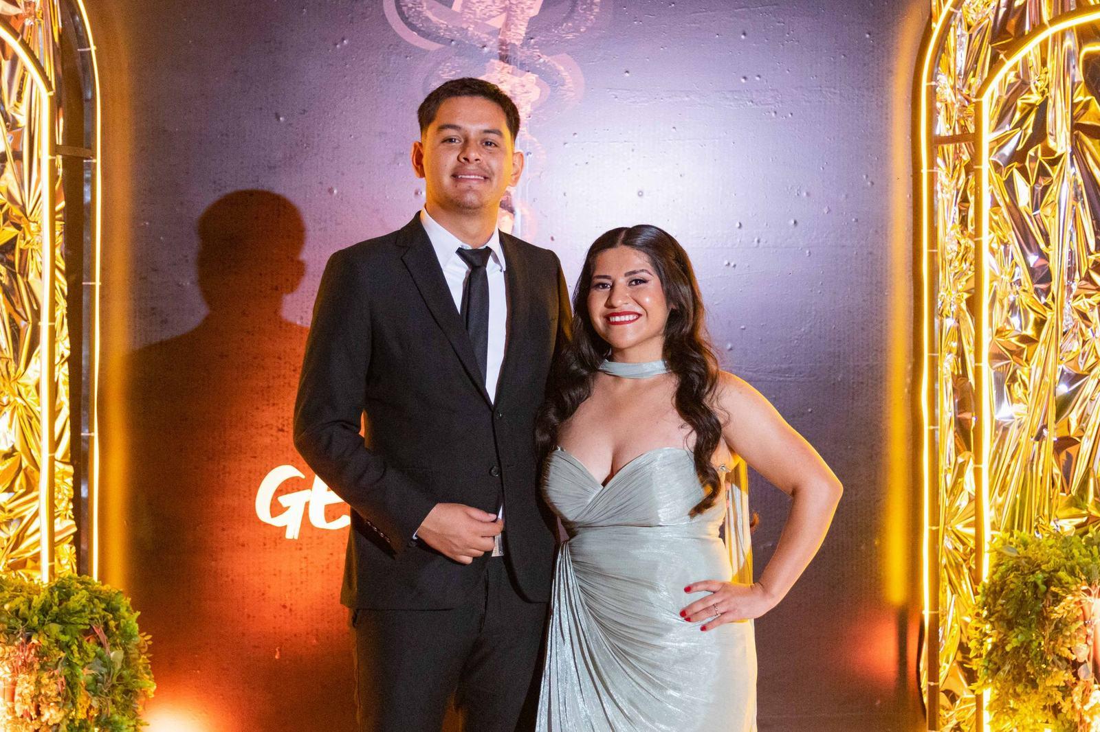 Couple posing at a gala in front of a gold floral arch