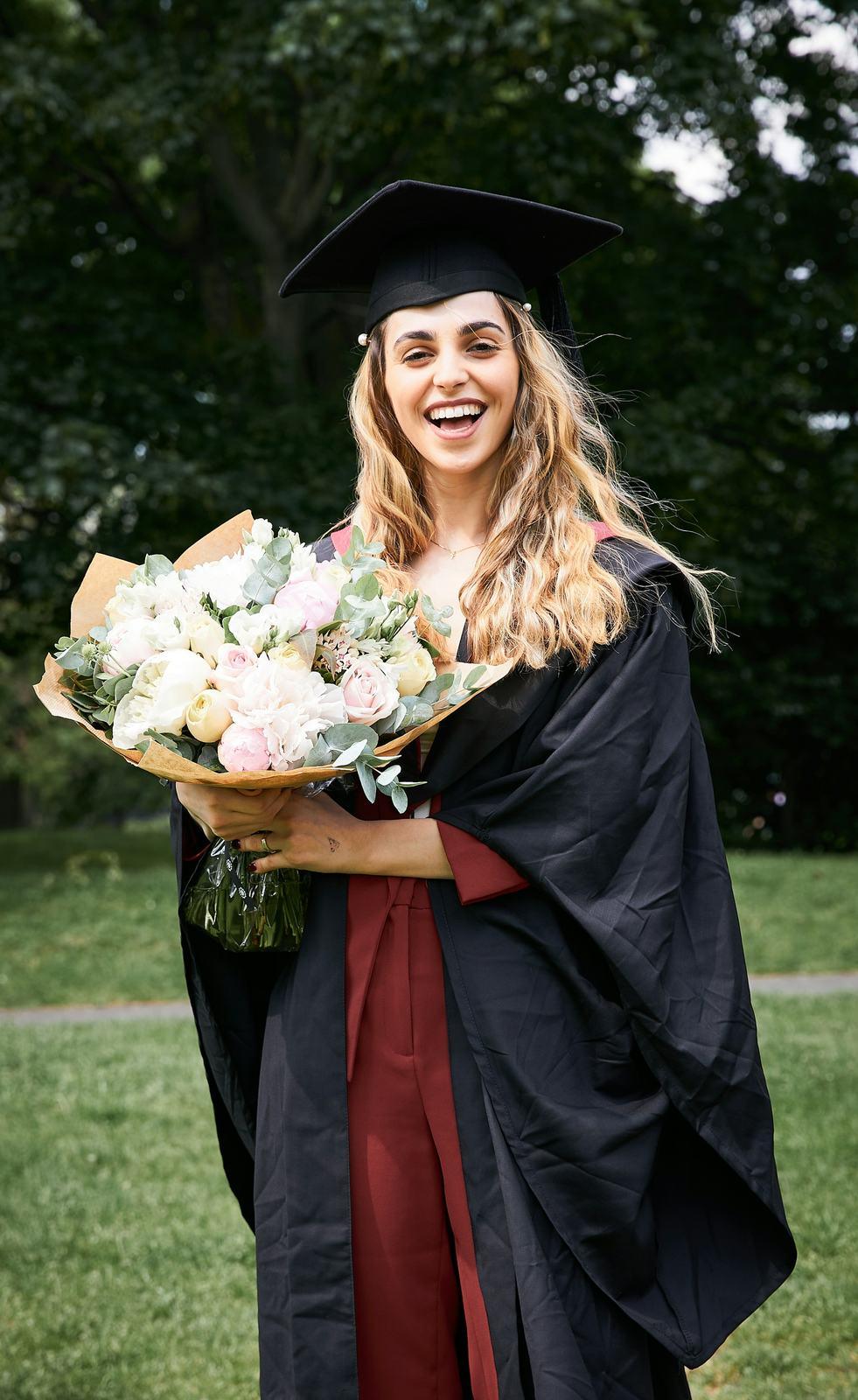 Graduate in cap and gown holding a bouquet