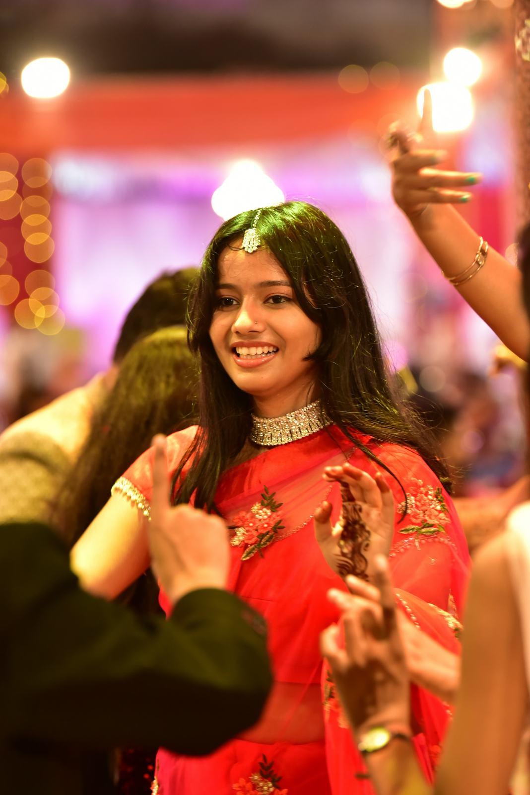 Guest in a red saree laughing on the sangeet dance floor