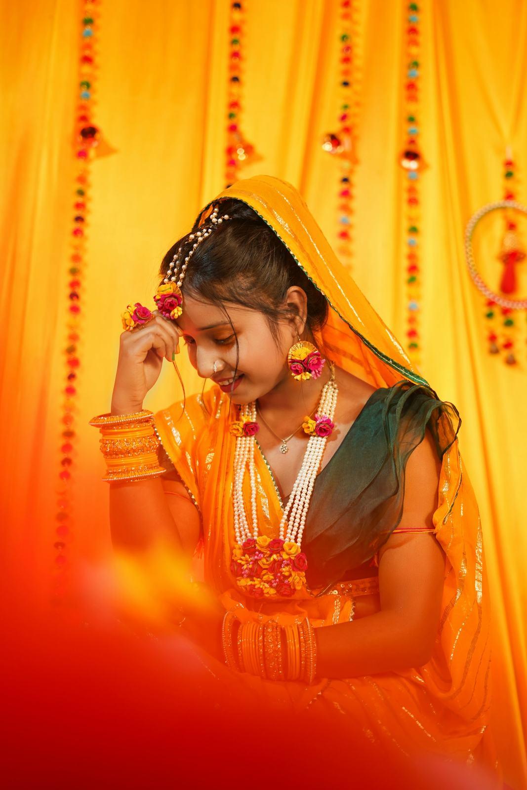 Bride in yellow at her haldi, surrounded by marigold drapes