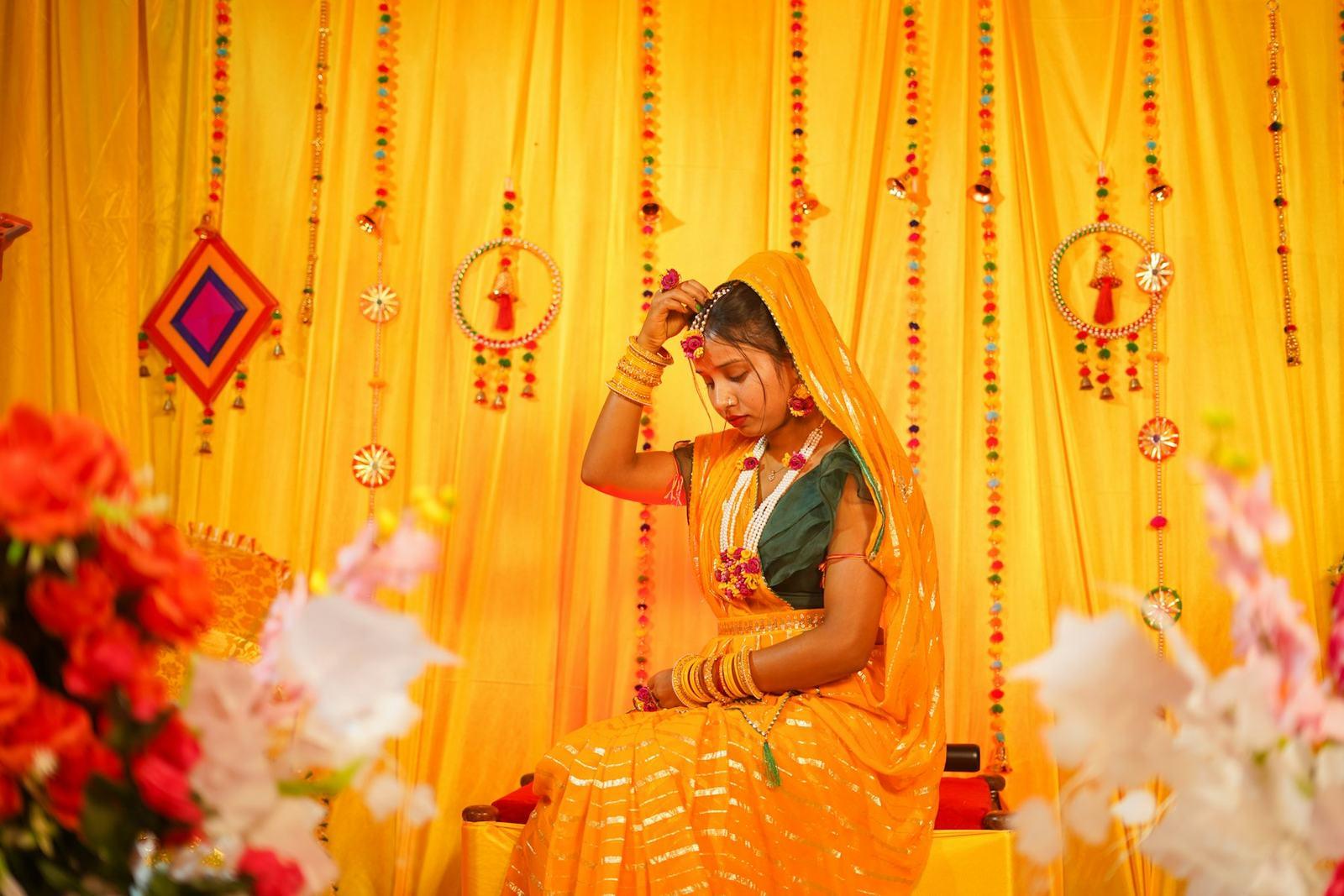 Bride seated beneath bright yellow haldi decor