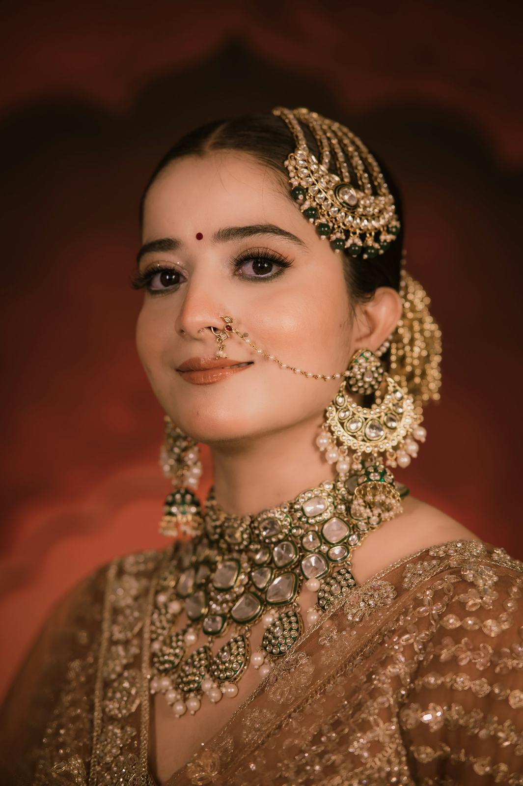 Bride in a gold lehenga with a maang tikka, smiling