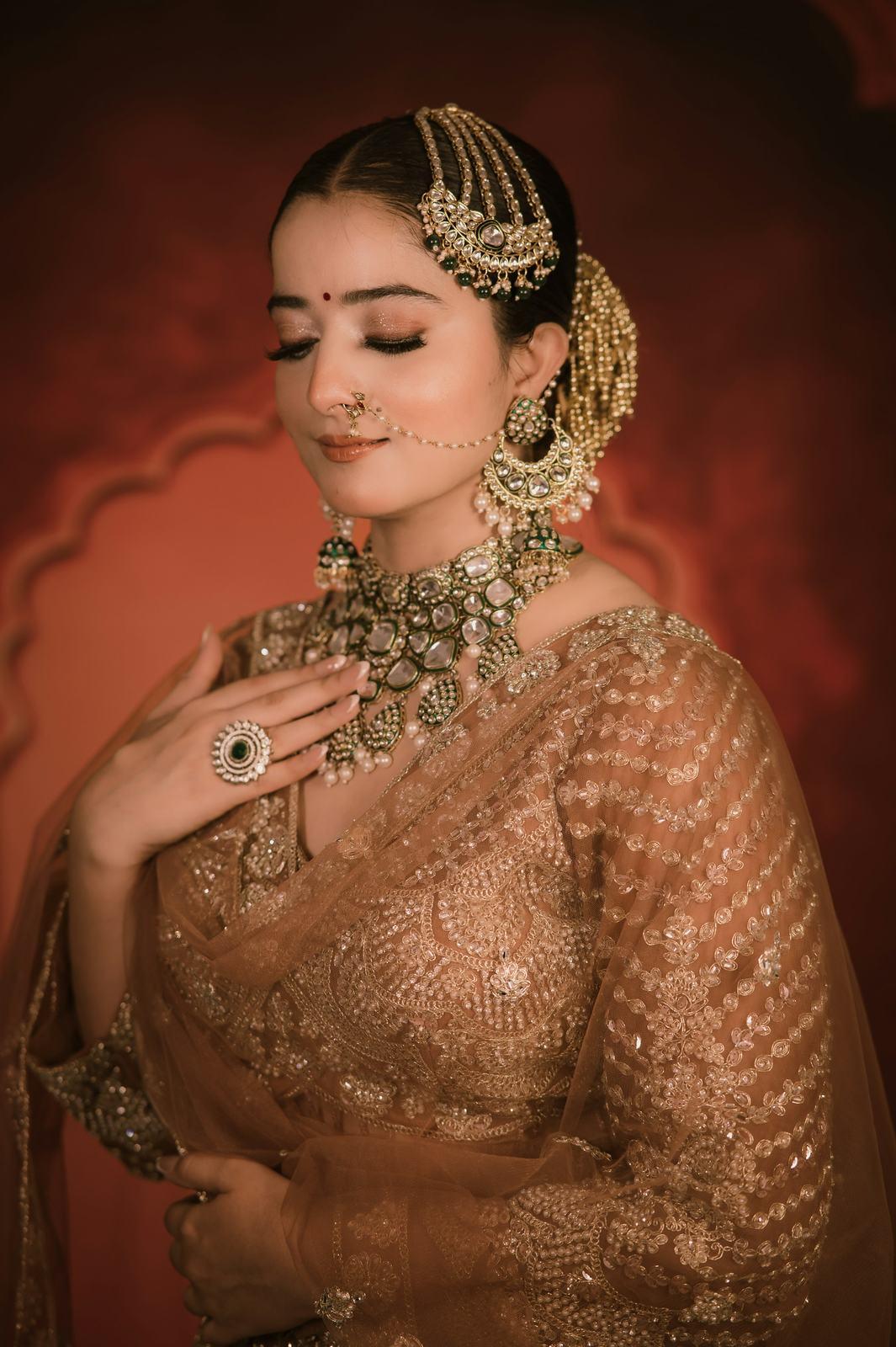 Bride in a gold lehenga adjusting her earring