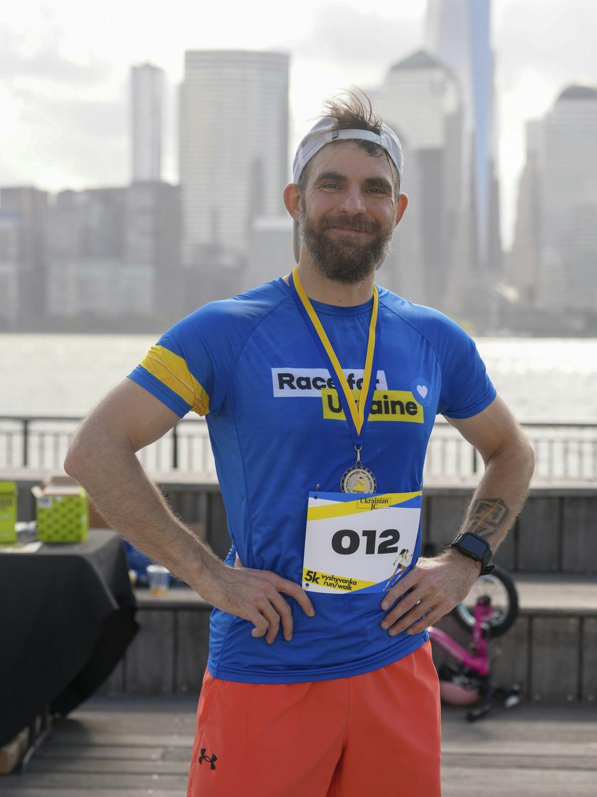 Runner with a race bib and finisher medal smiling after a marathon