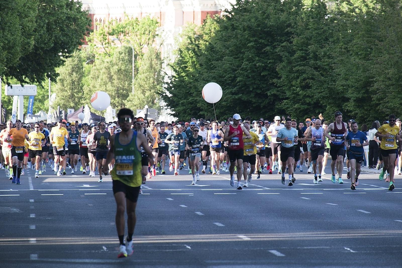 Runners filling a tree-lined road at the start of a city marathon