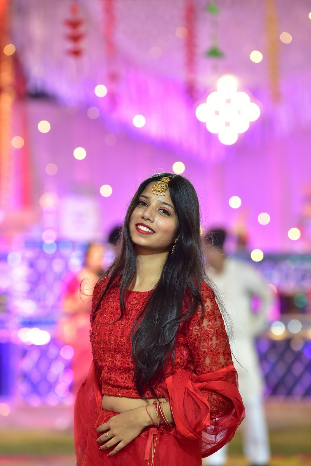 Guest in a red lehenga smiling at the sangeet