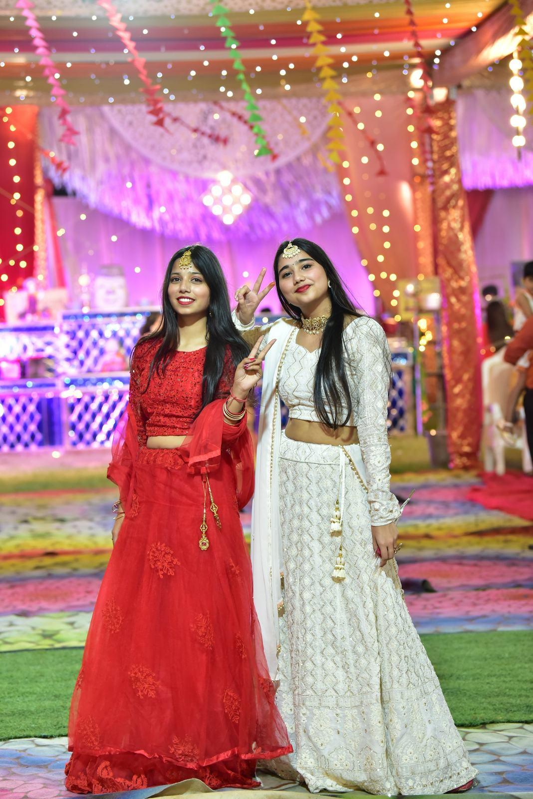 Two friends in red and ivory lehengas posing together