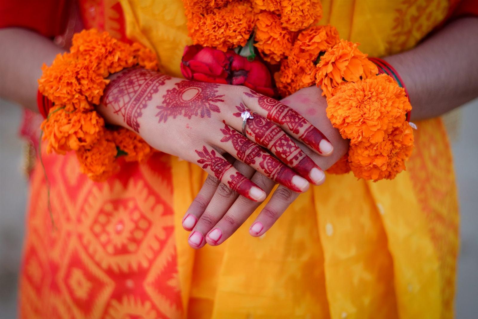Mehendi hands holding marigold flowers