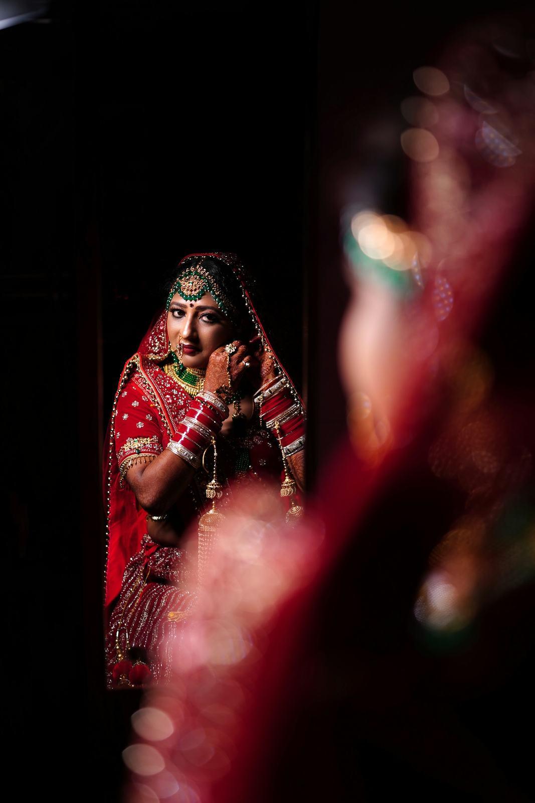 Bride in red reflected in a dark mirror