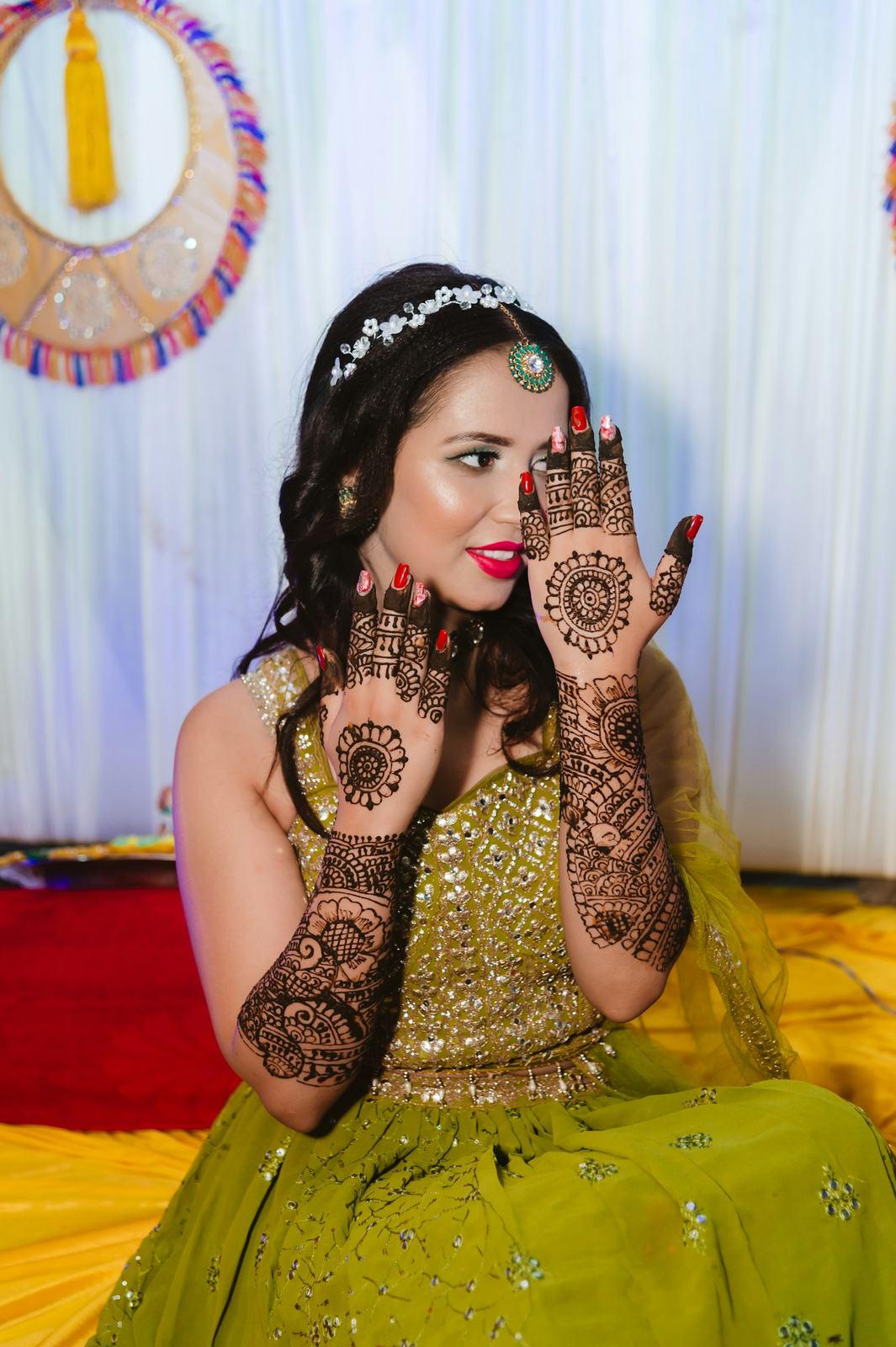 Bride showing her mehendi in a green lehenga
